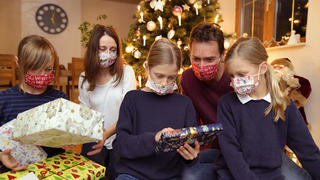 24.11.2020, Modelreleased. Symbolbild, Eine Familie im Allgäu sitzt mit Mund-Nasenschutz-Masken am Heiligen Abend vor dem Weihnachtsbaum im Wohnzimmer, Kontaktverbote und Ausgangsbeschränkungen machen der Bevölkerung zur Corona-Zeit das Leben schwer, die gewohnten Treffen unter den Familien sind dieses Jahr wegen der Pandemiebeschränkungen nur Eingeschränkt möglich. 24.11.2020, Familie feiert Weihnachten mit Corona-Einschränkungen 24.11.2020, Familie feiert Weihnachten mit Corona-Einschränkungen *** 24 11 2020, Modelreleased symbol picture, A family in the Allgäu sits with mouth nose-protection masks on Christmas Eve in front of the Christmas tree in the living room, contact bans and exit restrictions make life difficult for th 