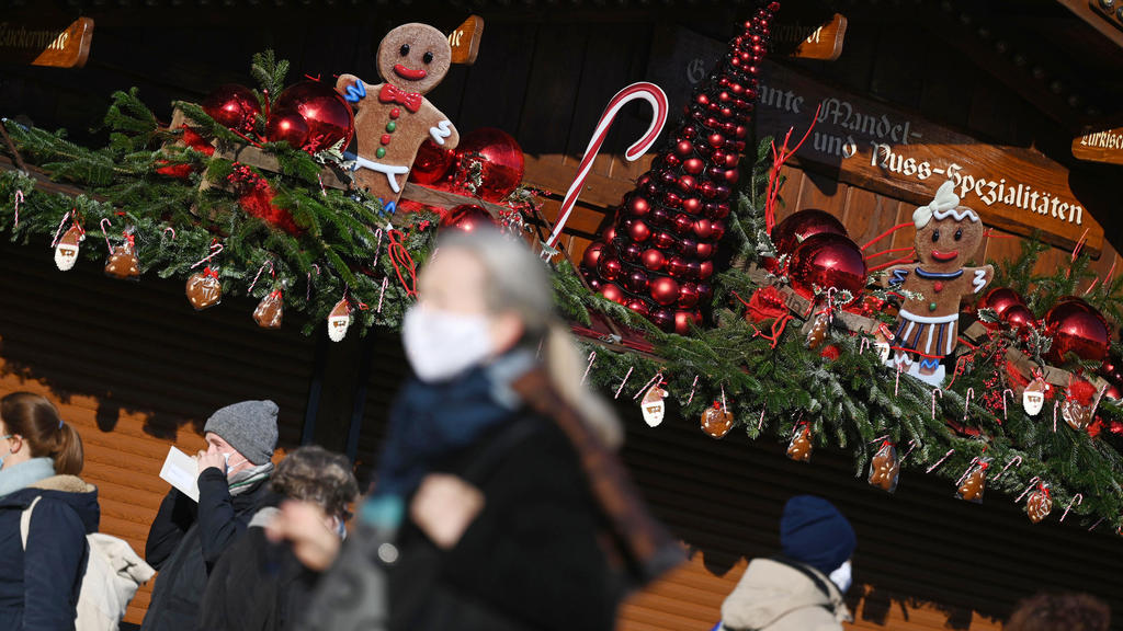 25.11.2020, Baden-Württemberg, Stuttgart: Passanten gehen an einem weihnachtlich geschmückten Stand in der Innenstadt vorbei. In der baden-württembergischen Landeshauptstadt findet aufgrund der Corona-Pandemie kein Weihnachtsmarkt statt. Vom 26. Nove