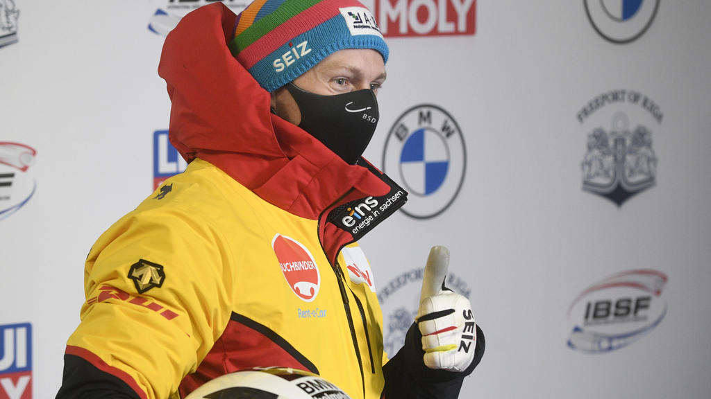 22.11.2020, Lettland, Sigulda: Bob: Weltcup, Zweierbob, Männer, 1. Durchgang: Francesco Friedrich aus Deutschland trägt Mund-Nasen-Schutz und gestikuliert bei der Preisverleihung. Foto: Roman Koksarov/AP/dpa +++ dpa-Bildfunk +++