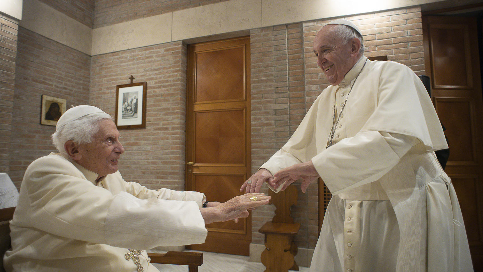 28.11.2020, Vatikan, Vatikanstadt: Papst Franziskus (r) gibt nach dem Konsortium dem emeritierten Papst Benedikt XVI. bei einem Besuch mit den ernannten Kardinälen die Hand. In einer für den Vatikan ungewöhnlichen Zeremonie angesichts der Corona-Pand