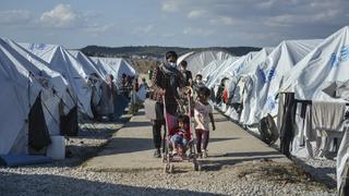 ARCHIV - 14.10.2020, Griechenland, Lesbos: Migranten gehen nach einem starken Regenfällen durch das Flüchtlingslager «Kara Tepe». (zu dpa "Spiegel: Deutschland soll bis zu 5000 Flüchtlinge mehr aufnehmen") Foto: Panagiotis Balaskas/AP/dpa +++ dpa-Bildfunk +++