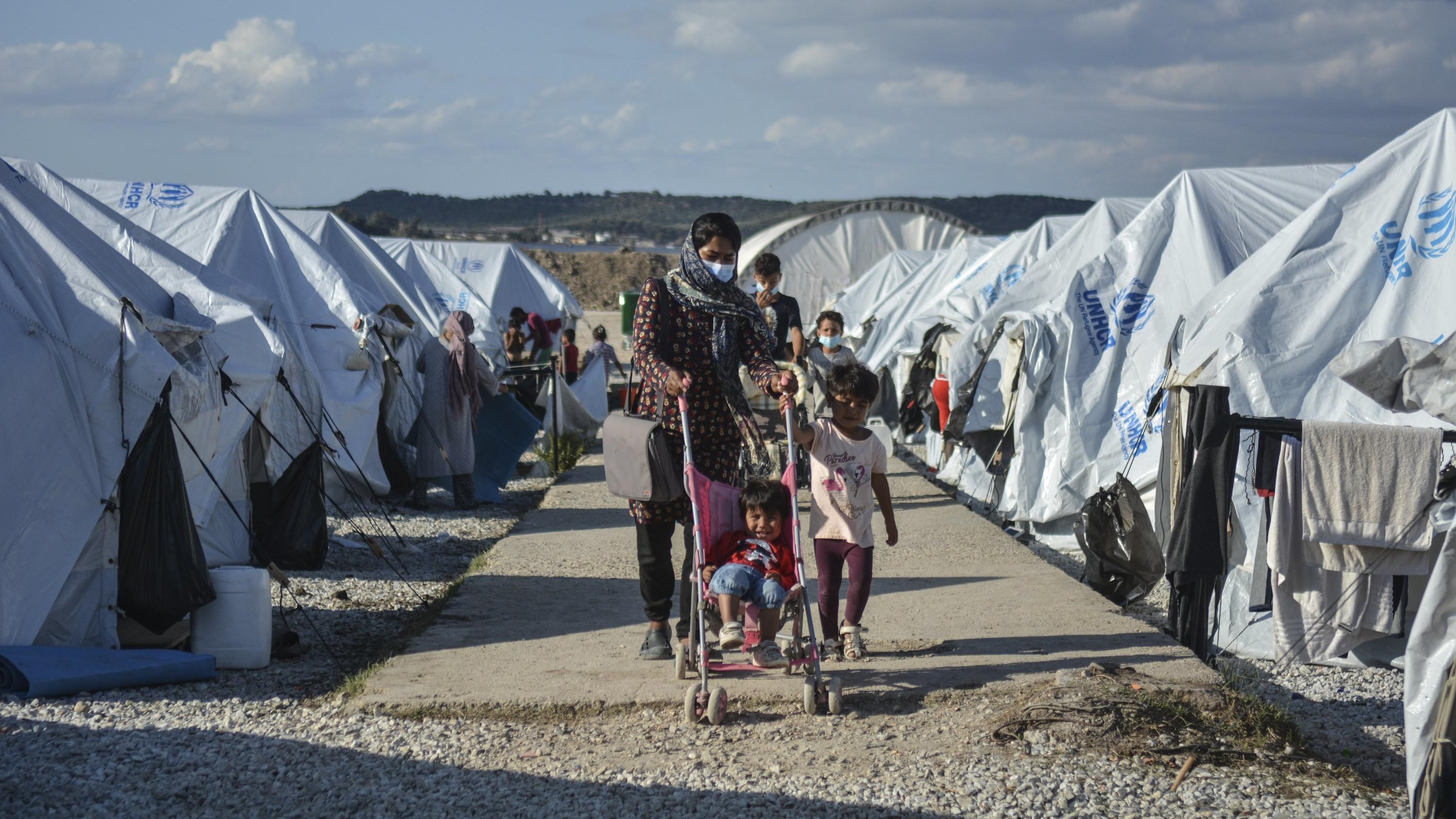ARCHIV - 14.10.2020, Griechenland, Lesbos: Migranten gehen nach einem starken Regenfällen durch das Flüchtlingslager «Kara Tepe». (zu dpa "Spiegel: Deutschland soll bis zu 5000 Flüchtlinge mehr aufnehmen") Foto: Panagiotis Balaskas/AP/dpa +++ dpa-Bil