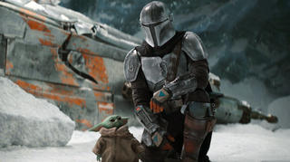 This image released by Disney Plus shows Pedro Pascal, as Din Djarin, right, with The Child, in a scene from "The Mandalorian," premiering its second season on Friday. (Disney Plus via AP)