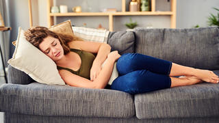 Frau mit Bauchschmerzen auf dem Sofa