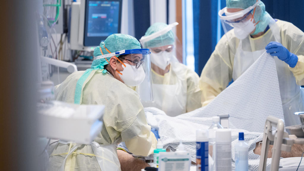 ARCHIV - 11.11.2020, Baden-Württemberg, Stuttgart: Ayse Yeter (l), Krankenschwester und Stationsleitung der Intensivstation für Covid-19 Patienten des Klinikum Stuttgart, versorgt in einem Patientenzimmer einen Covid-19-Patienten, der im künstlichen