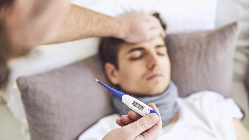 Close-up of doctor examining patient s temperature sleeping on bed at home model released Symbolfoto property released UKOF00029