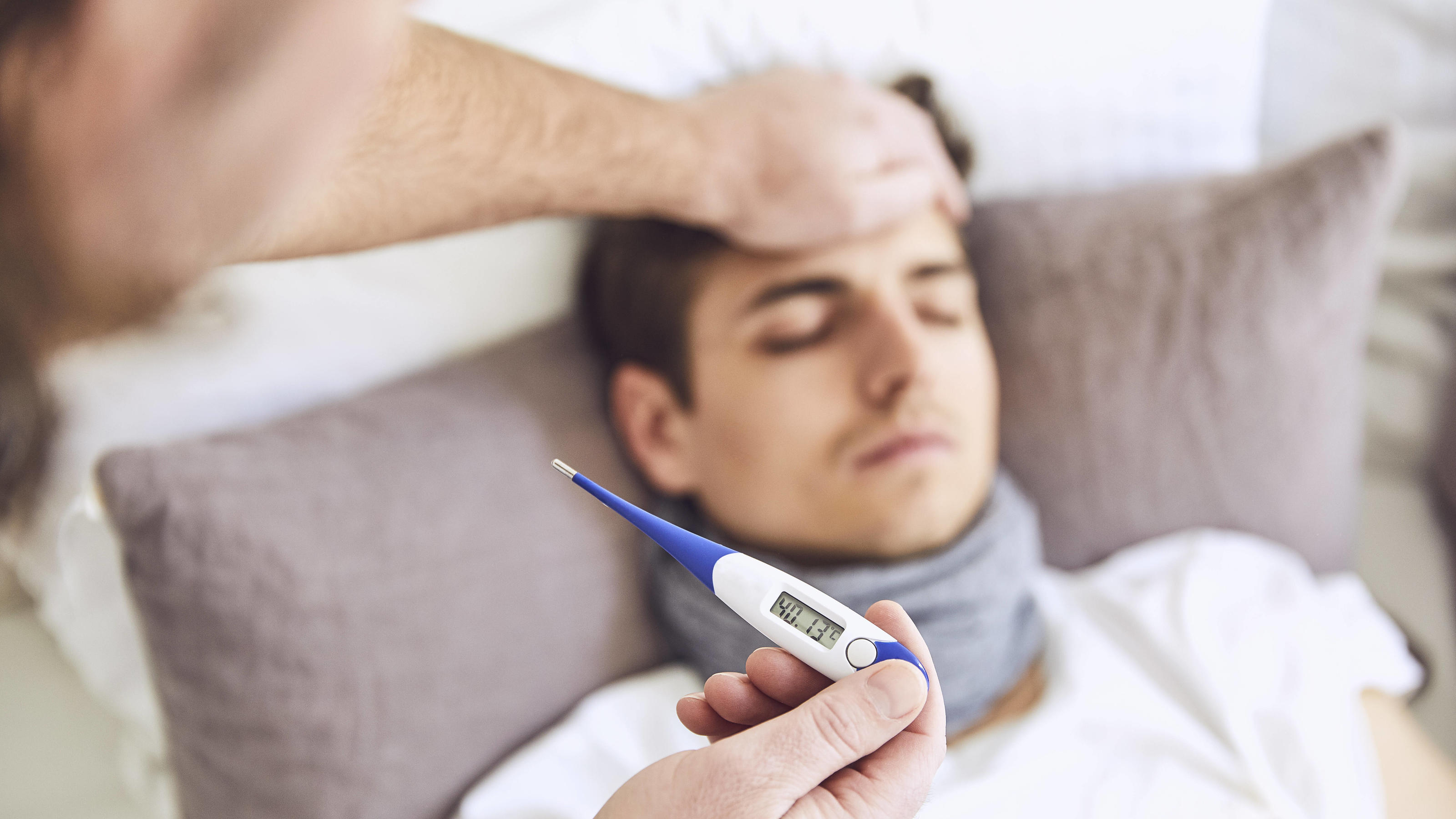  Close-up of doctor examining patient s temperature sleeping on bed at home model released Symbolfoto property released UKOF00029