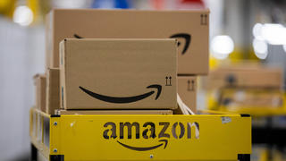 ARCHIV - 08.12.2020, Nordrhein-Westfalen, Mönchengladbach: Pakete liegen in einem Logistikzentrum des Versandhändlers Amazon auf einem Wagen. Die US-Internetriesen Google und Amazon sollen in Frankreich wegen Verstößen gegen Gesetzesregeln für Cookies Millionenbußen zahlen. (zu dpa «Millionen-Strafen für Google und Amazon in Frankreich») Foto: Rolf Vennenbernd/dpa +++ dpa-Bildfunk +++