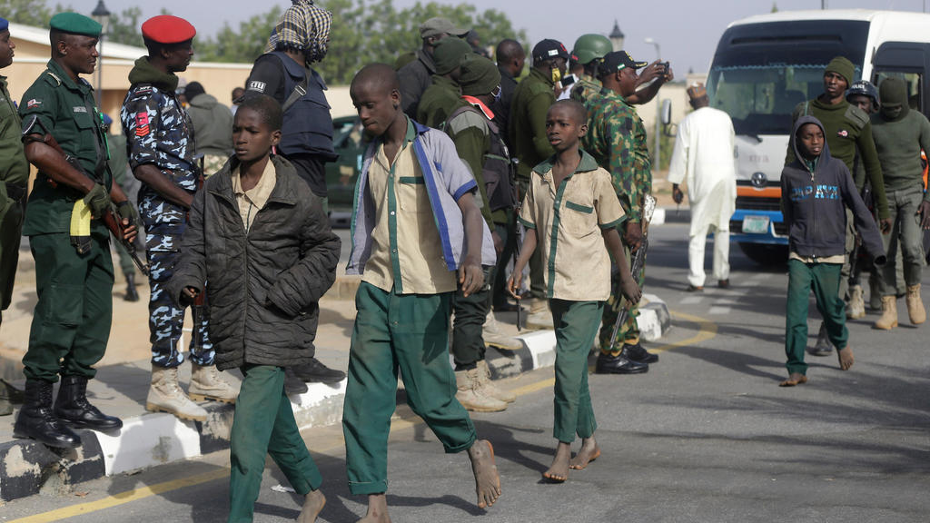 18.12.2020, Nigeria, Katsina: Nigerianische Militärmitglieder und Beamte eskortieren wieder freigelassene Schüler, die Anfang der Woche aus der Schule «Government Science Secondary School» in Kankara in der Nordregion Katsina von Extremisten entführt