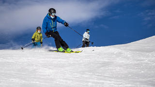 ARCHIV - 28.11.2020, Schweiz, Verbier: Skifahrer mit Mund-Nasen-Schutz fahren eine Piste im Walliser Skigebiet hinunter. Die Schweiz steht derzeit unter europäischem Druck im Zusammenhang mit der Eröffnung ihrer Skigebiete. So wird Frankreich beispielsweise eine siebentägige Isolationsperiode für diejenigen Bürger einführen, die in den Ferien zum Skifahren ins Ausland fahren wollen. Foto: Jean-Christophe Bott/KEYSTONE/dpa +++ dpa-Bildfunk +++
