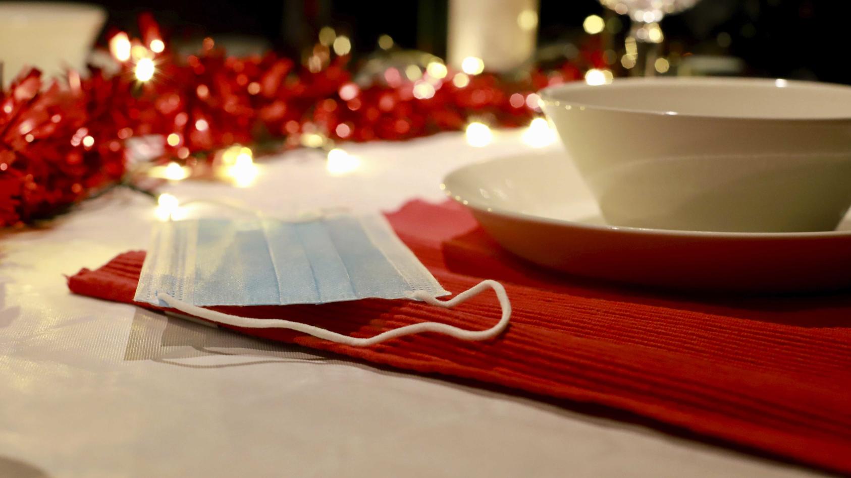 ARCHIV - 18.11.2020, Niederlande, ---: Eine Mund-Nasen-Bedeckung liegt auf einem weihnachtlich gedeckten Tisch. Die Weltgesundheitsorganisation (WHO) legt den Europäern ans Herz, an Weihnachten und Neujahr bei Festen mit Familie und Freunden einen Mu