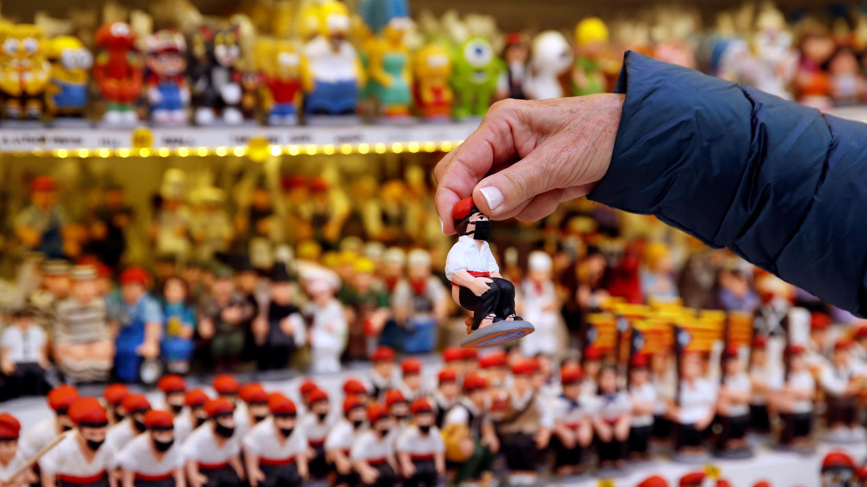 A woman holds a clay "caganer" figure wearing a mask, which symbolises defecation and fertilisation of the earth, and is believed to bring prosperity and luck for the coming year, at the Santa Llucia Christmas market in central Barcelona, during the 