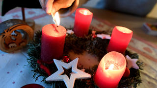 ARCHIV - 22.12.2019, Garmisch-Partenkirchen: ILLUSTRATION - Eine Frau zündet am vierten Advent die vierte Kerze am Adventskranz an. Foto: Angelika Warmuth/dpa +++ dpa-Bildfunk +++