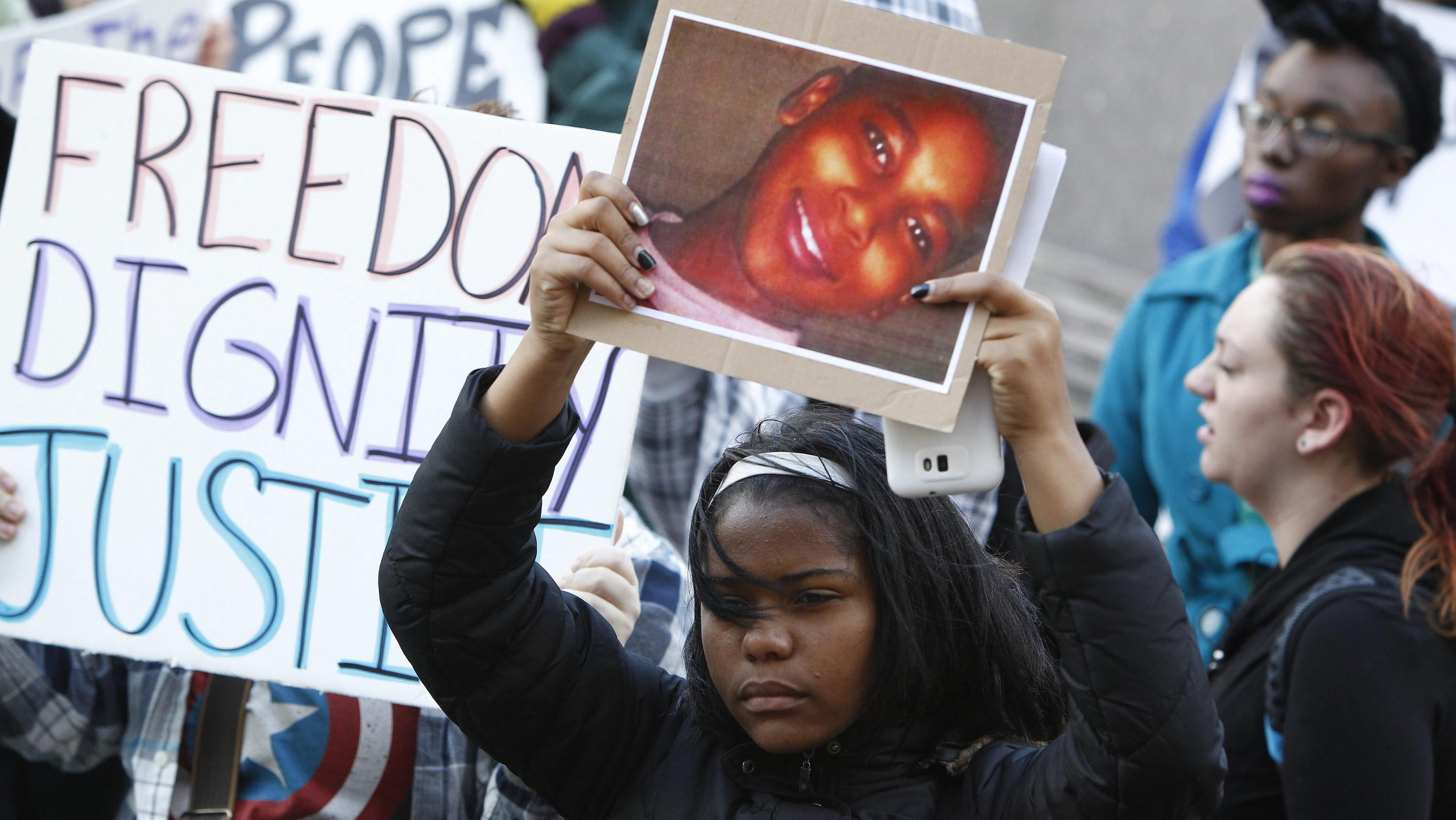 ARCHIV - 24.11.2014, USA, Cleveland: Ein Demonstrant hält bei einer Kundgebung auf dem Public Square ein Plakat mit einem Bild von Tamir Rice. Nach den tödlichen Schüssen auf einen zwölfjährigen schwarzen Jungen in den USA im Jahr 2014 hat das Justiz