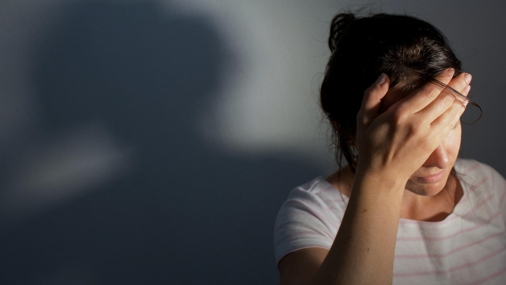 Junge Frau hat Kopfschmerzen und hält sich die Hand vor die Stirn