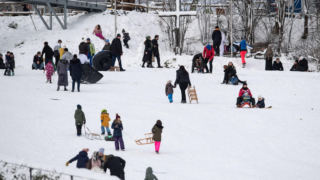01.01.2021, Nordrhein-Westfalen, Winterberg: Ausflügler tummeln sich mit ihren Schlitten auf einem verschneiten Hang. Die Stadt Winterberg bittet wegen der Corona-Pandemie auf Besuche in dem Wintersportort und an den Pisten im Sauerland zu verzichten