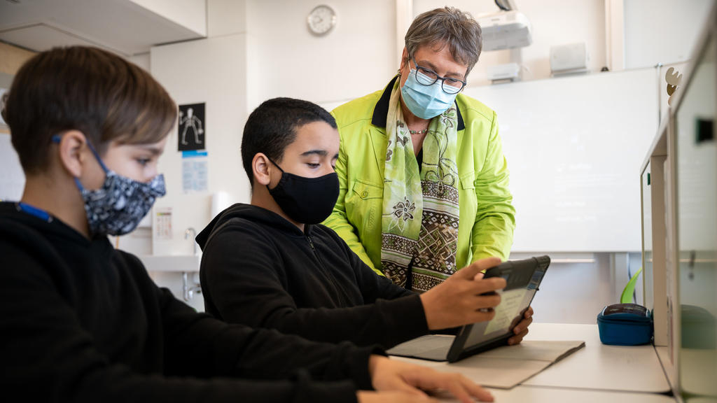25.11.2020, Baden-Württemberg, Ditzingen: Eine Lehrerin, die einen Mund- und Nasenschutz trägt, spricht in einer siebten Klasse einer Gemeinschaftsschule mit Schülern, die ebenfalls Maske tragen. Der Verband Bildung und Erziehung (VBE) informiert auf