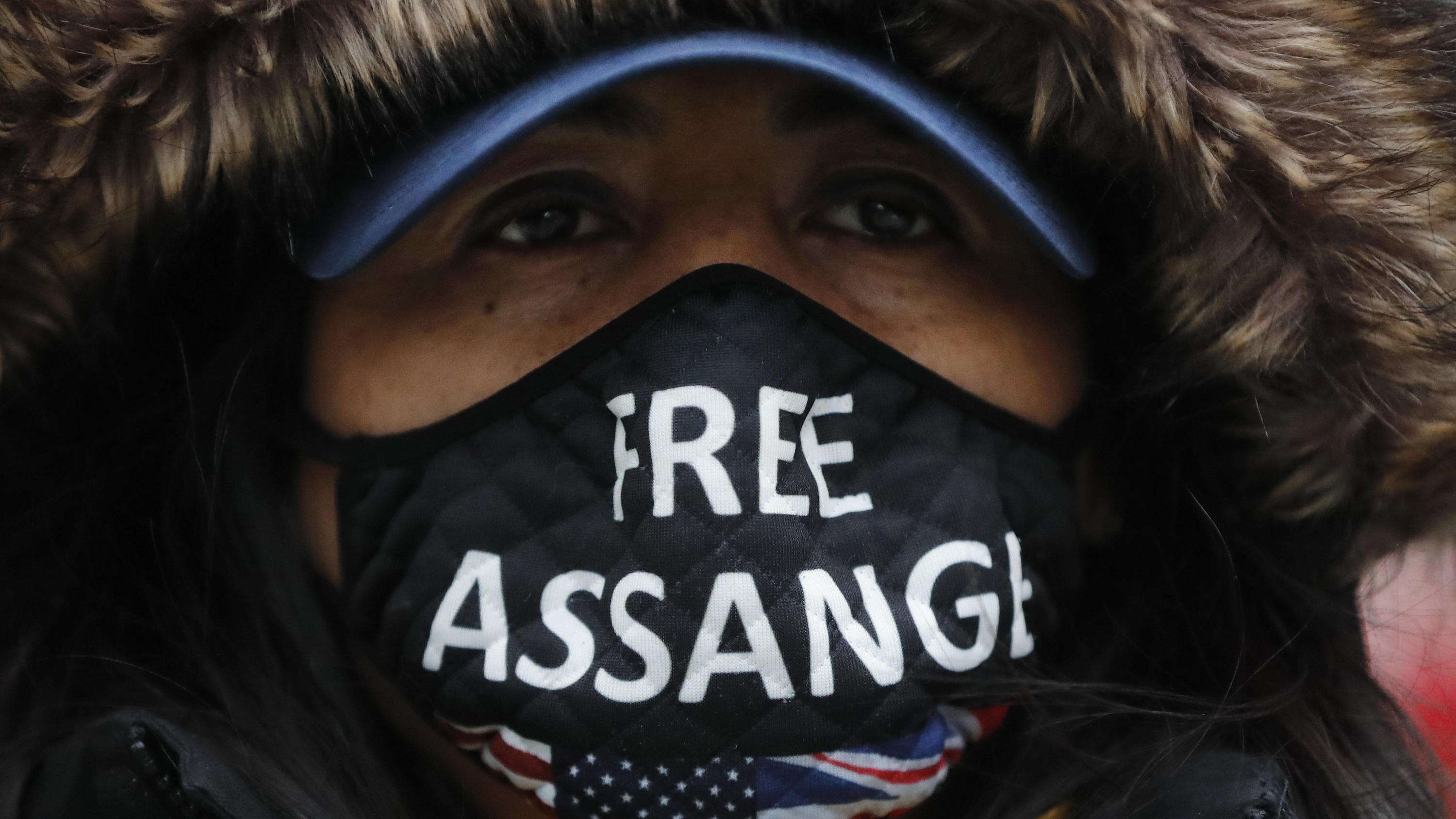 A Julian Assange supporter wears a face mask bearing his name outside the Old Bailey in London, Monday, Jan. 4, 2021. Judgement is to be made by Judge Vanessa Baraitser on Julian Assange's his extradition hearing to the US. Assange has been charged u
