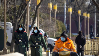 09.01.2021, China, Beijing: Chinesische paramilitärische Polizisten mit Mund-Nasen-Schutz patrouillieren entlang einer Straße. Foto: Mark Schiefelbein/AP/dpa +++ dpa-Bildfunk +++