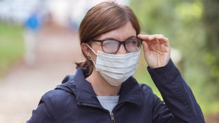 Frau mit beschlagener Brille und Mund-Nasen-Maske