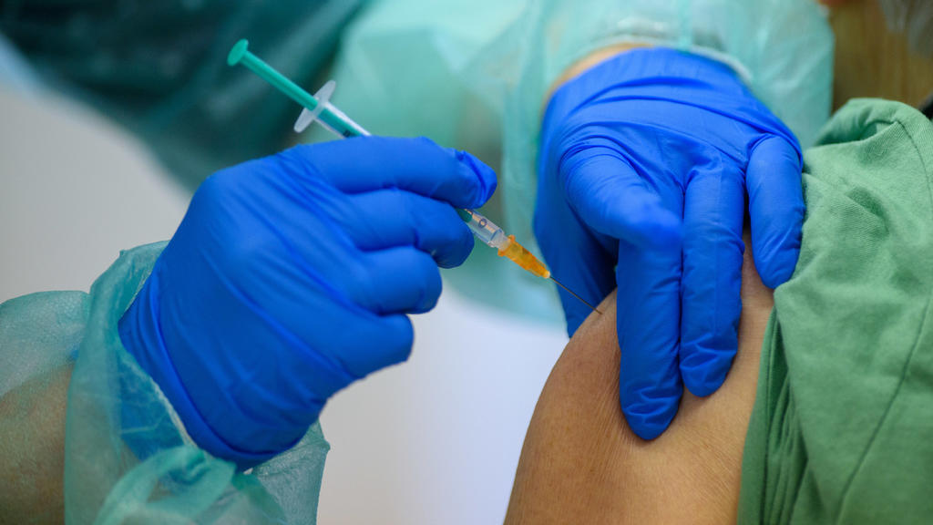11.01.2021, Sachsen-Anhalt, Staßfurt: Eine Mitarbeiterin des Impfzentrums des Salzlandkreises spritzt einer Frau eine Impfdosis gegen das Coronavirus. Parallel zu den verschärften Corona-Regeln wurde im Kampf gegen die Pandemie in Sachsen-Anhalt das