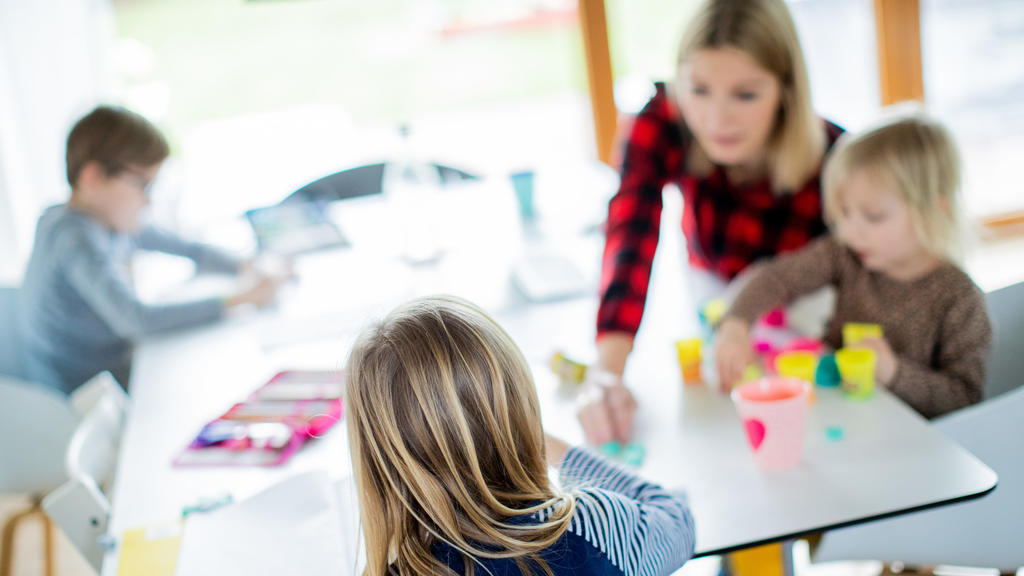 dpatopbilder - 14.01.2021, Nordrhein-Westfalen, Haltern am See: Eine Lehrerin sitzt mit ihren drei Kindern im Wohnzimmer, unterrichtet ihre Schüler einer Berufsschule im Distanzunterricht und hilft ihren Kindern bei ihren Aufgaben für die Schule. Um