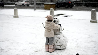 08.01.2021, Spanien, Madrid: Ein Mädchen spielt mit einem Schneemann auf der Straße in Madrid. Das Sturmtief «Filomena» sorgt im Sonnenland Spanien für Rekordkälte, viel Schnee und einiges Chaos. Foto: Óscar Cañas/EUROPA PRESS/dpa +++ dpa-Bildfunk +++