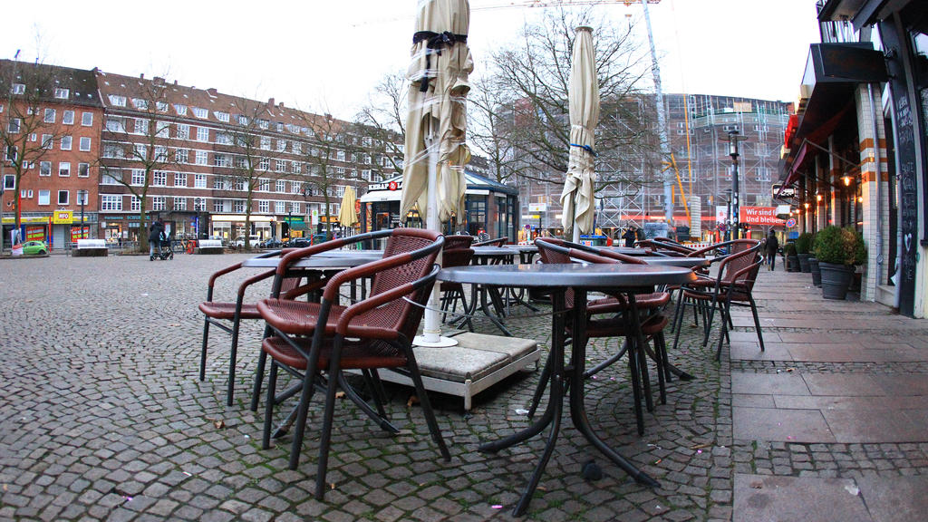 Aufeinander gestapelte Stühle stehen vor einem geschlossenen Restaurant auf dem menschenleeren Winterhuder Marktplatz in Hamburg. Winterhude Hamburg *** Chairs stacked on top of each other stand in front of a closed restaurant on the deserted Winter