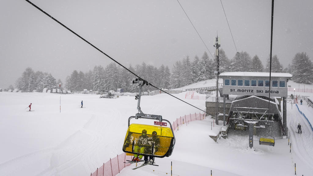05.12.2020, Schweiz, St. Moritz: Zwei Skifahrer mit Mund-Nasen-Schutz fahren mit einem Sessellift. Aufgrund starker Schneefälle und starken Windes hat der internationale Skiverband (FIS) beschlossen, das heutige Super-G-Rennen der Frauen im Ski-Weltc
