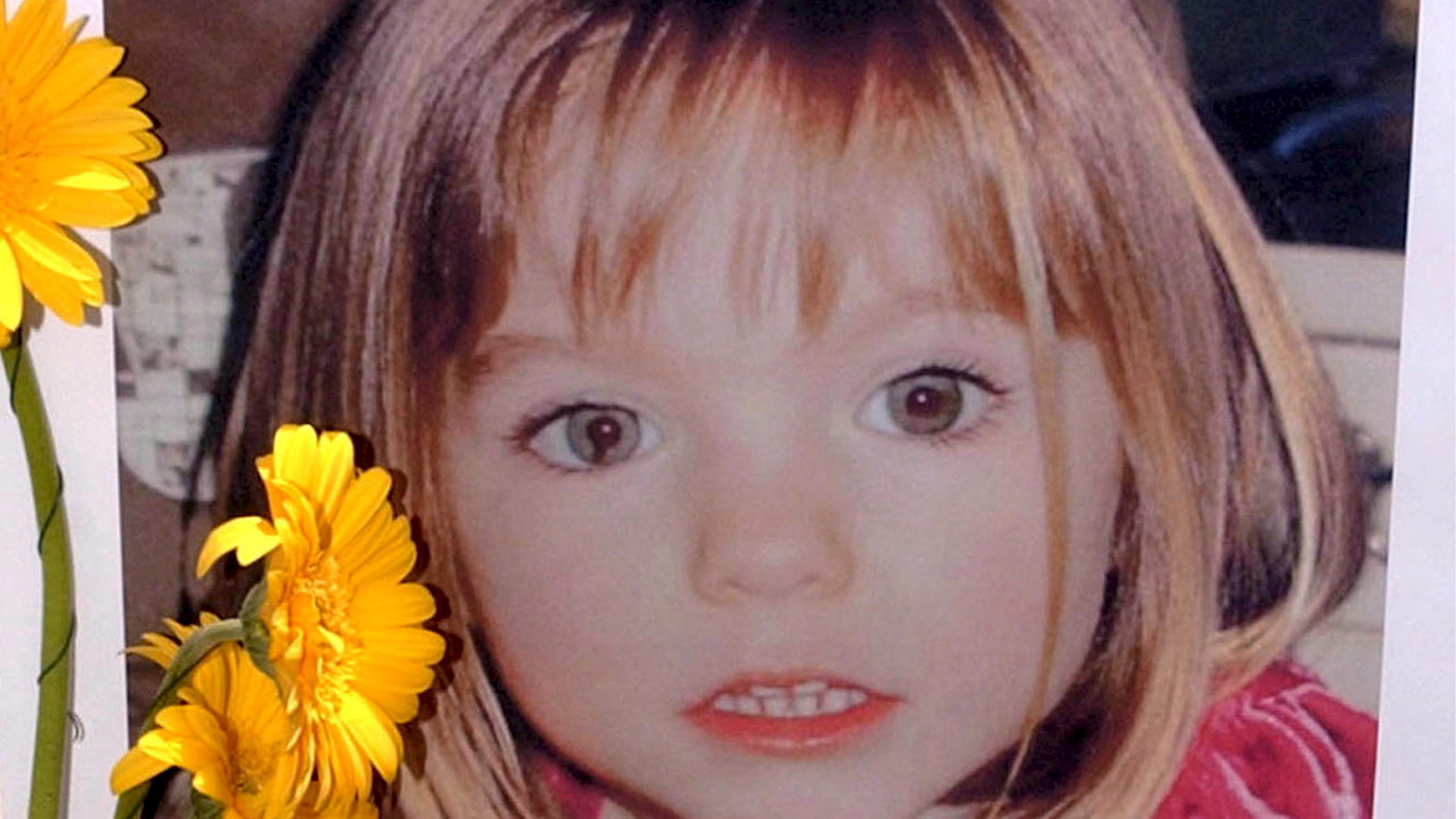 ARCHIV - 12.05.2007, Portugal, Lagos: Blumen stehen vor einem Bild, das die verschwundenen Madeleine McCann (Maddie) auf einem Foto zeigt, das ihre Eltern im Zusammenhang mit dem Verschwinden des Kindes veröffentlich haben. (zu dpa "Verdächtiger im F
