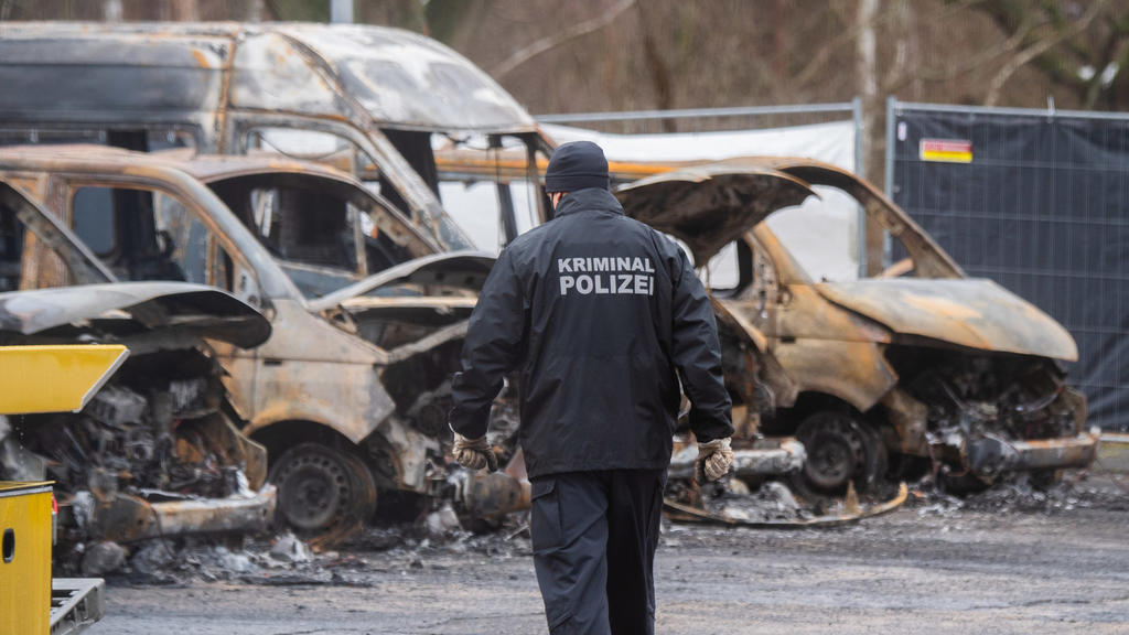 11.01.2021, Niedersachsen, Braunschweig: Ein Mitarbeiter der Kriminalpolizei geht vor ausgebrannten Fahrzeugen auf dem Gelände der niedersächsischen Landesaufnahmebehörde. Nach den mutmaßlich politisch motivierten Brandanschlägen auf Aufnahmebehörden