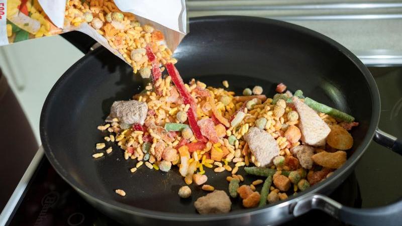 Zubereitung des Fertiggerichtes "Hähnchen Paella" in einer Pfanne. Foto: Peter Steffen/dpa/Symbol