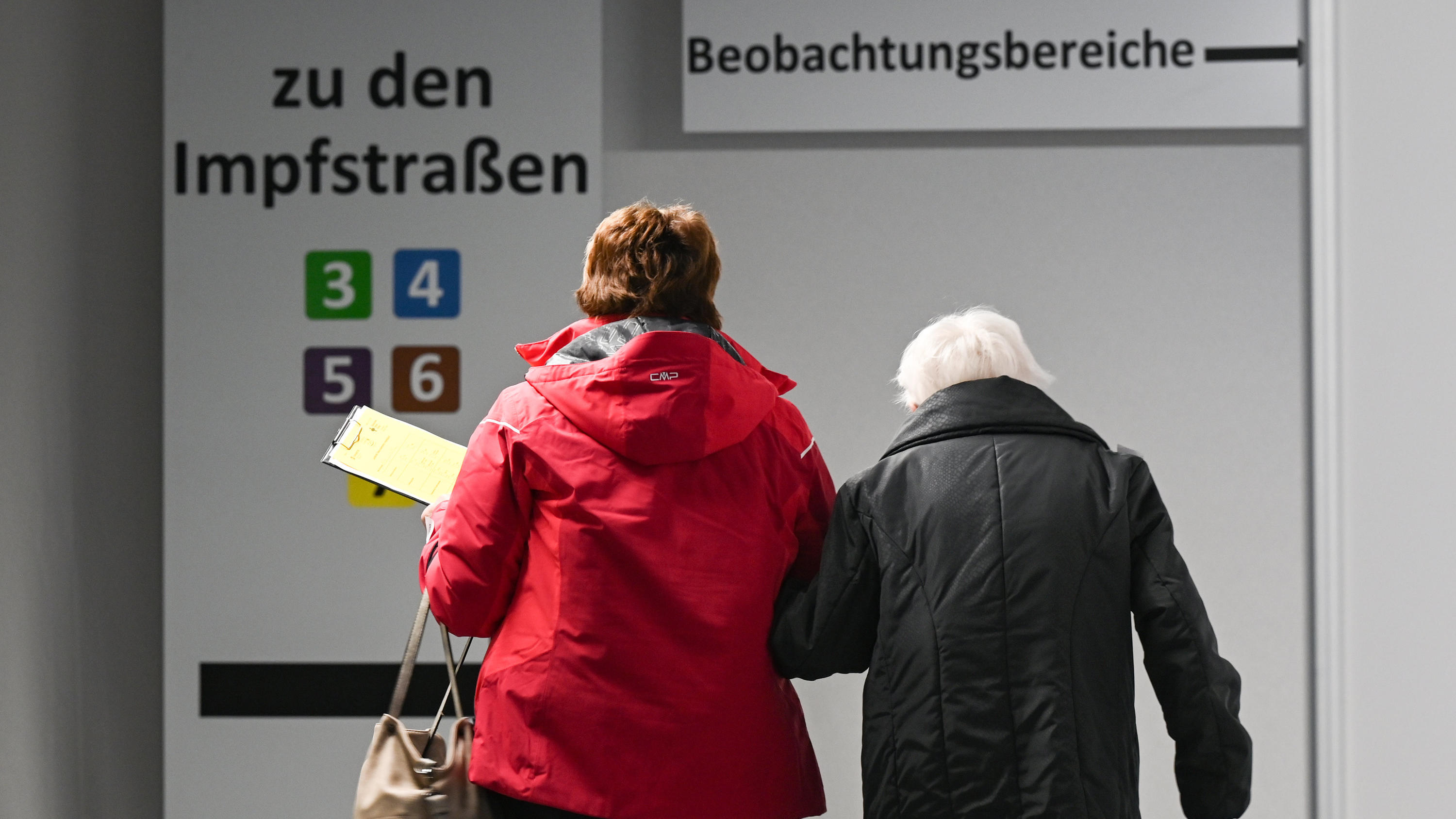 Hessen, Heuchelheim: Eine ältere Frau (r) wird im Impfzentrum zu einer Impfkabine begleitet. Seit 19. Januar sind die ersten sechs regionalen Impfzentren in Hessen geöffnet.