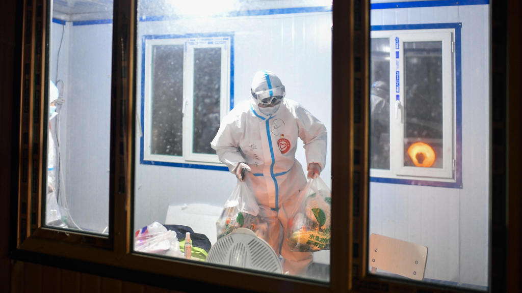 24.01.2021, China, Tonghua: Du Sicheng, ein Freiwilliger der Gemeinde Dongchang, überbringt Quarantänebewohnern Güter des täglichen Bedarfs an einem Kontrollpunkt einer Wohngemeinschaft in der Provinz Jilin im Nordosten der Volksrepublik China. Der 2