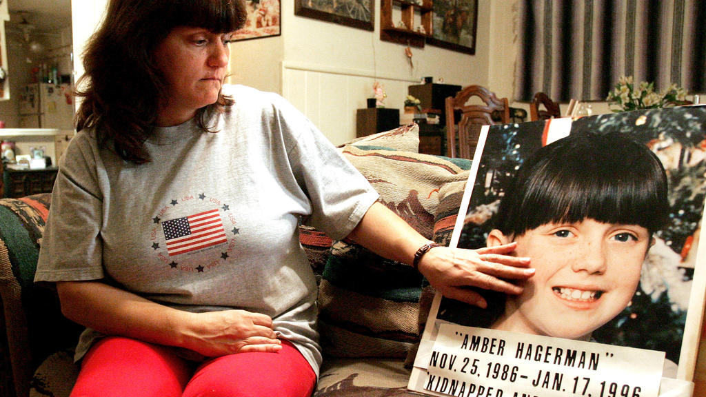 FILE - In this Jan. 12, 2006 file photo, Donna Norris touches a photo of her daughter, Amber Hagerman, at her Hurst, Texas, home. The 1996 slaying of the North Texas girl that led to the Amber Alert notification system to find missing children remain