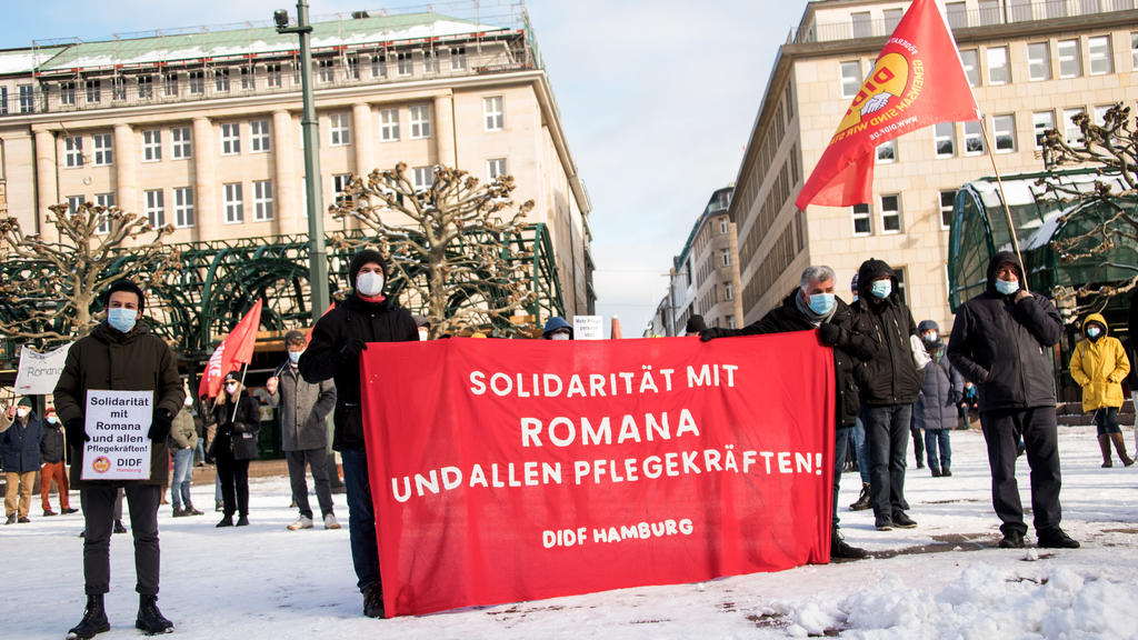31.01.2021, Hamburg: Teilnehmer einer Kundgebung gegen die Kündigung der Asklepios-Beschäftigten Romana K., die über Missstände in den Krankenhäusern während der Corona-Pandemie öffentlich berichtet hatte, stehen auf dem Rathausmarkt und halten ein B