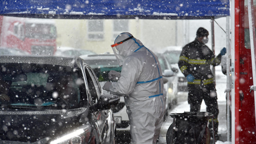 30.01.2021, Tschechien, Mühlbach: Am Tag der Eröffnung einer Drive-In-Testanlage für Pendler am tschechisch-deutschen Grenzübergang in Mühlbach (Pomezi nad Ohri) nimmt ein Mitarbeiter des Gesundheitswesens aus einem Auto heraus einen Abstrich für ein