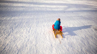 19.01.2021, Bayern, München: Ein Kind fährt auf einem Schlitten im Schnee einen Hügel im Stadtteil Haidhausen hinab. Foto: Peter Kneffel/dpa +++ dpa-Bildfunk +++