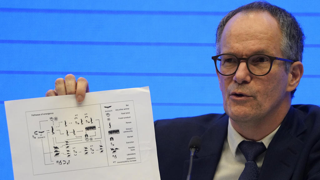 Peter Ben Embarek, of the World Health Organization team holds up a chart showing pathways of transmission of the virus during a joint press conference held at the end of the WHO mission in Wuhan in central China's Hubei province on Tuesday, Feb. 9,