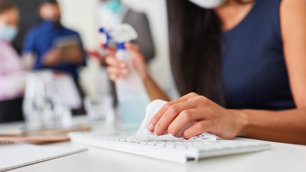 Frau im Büro desinfiziert Tastatur