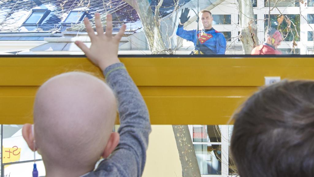 Kind winkt Superman am Fenster