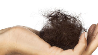 Weibliche Hand hält einen großen dunklen Haarballen