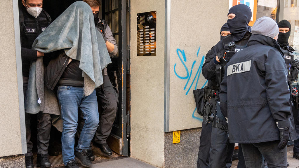 18.02.2021, Berlin: Ein Mann wird bei einer Razzia, mit einer Decke über dem Kopf, von der Polizei abgeführt. Mit einer Großrazzia ist die Polizei am Donnerstag gegen Clankriminalität in Berlin und Umgebung vorgegangen. Foto: Christophe Gateau/dpa -