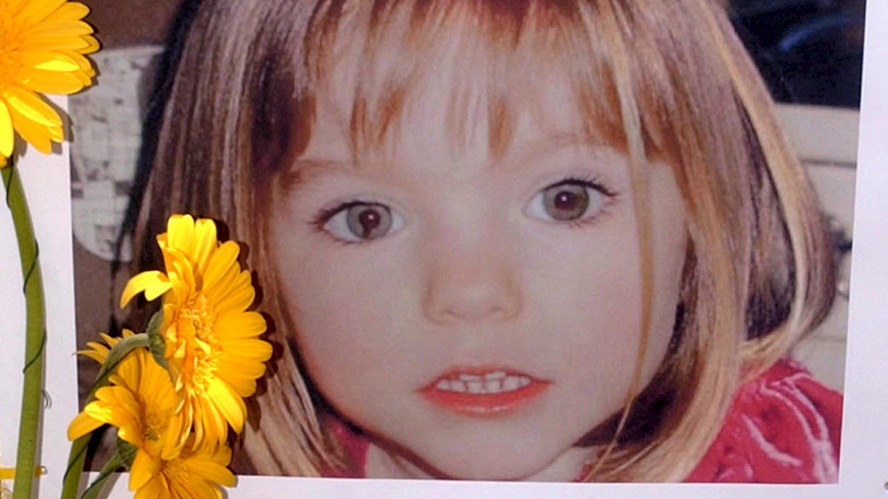 ARCHIV - 12.05.2007, Portugal, Lagos: Blumen stehen vor einem Bild, das die verschwundenen Madeleine McCann (Maddie) auf einem Foto zeigt, das ihre Eltern im Zusammenhang mit dem Verschwinden des Kindes veröffentlich haben. (zu dpa: "Fall Maddie: Erm