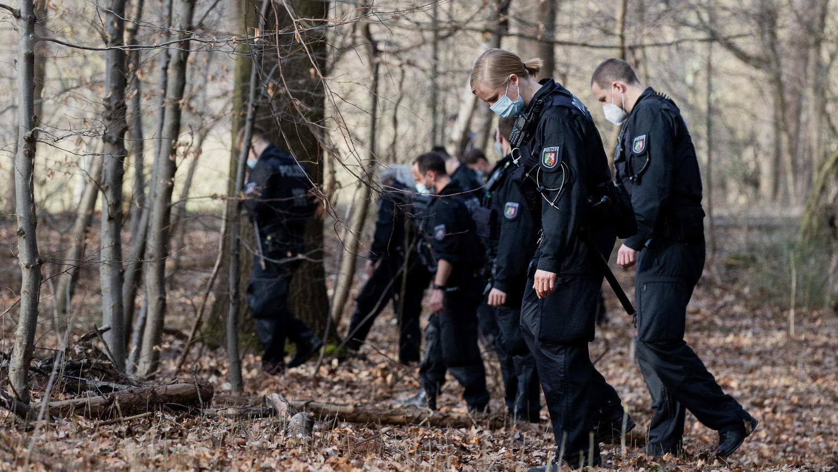 25.02.2021, Nordrhein-Westfalen, Köln: Polizeibeamte und Kriminalbeamte durchsuchen ein Waldstück im Stadtwald nach Spuren. Nach der Vergewaltigung einer Joggerin im Kölner Stadtwald befürchtet die Polizei eine Wiederholungstat. Darauf deute das atyp