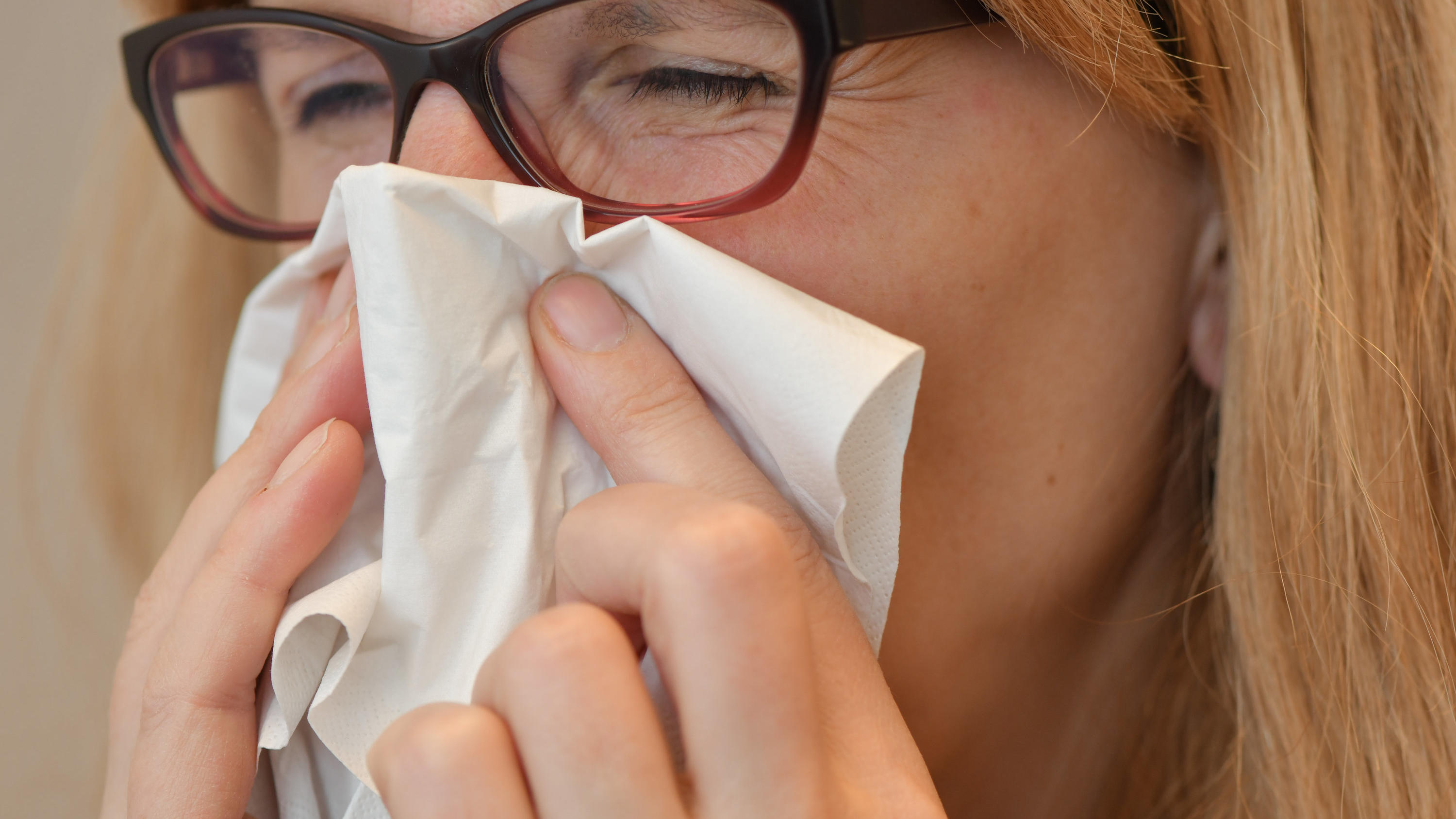 Eine Frau mit Brille benutzt ein Taschentuch. Die Maßnahmen zur Bekämpfung der Corona-Pandemie halten auch andere Infektionskrankheiten in Schach.