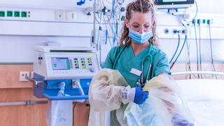 Krankenhausmitarbeiterin zieht sich Schutzkleidung an