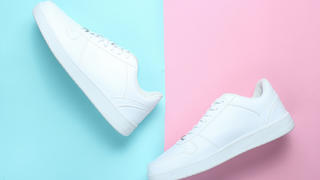 Weiße Sneaker vor pinkem und blauem Hintegrund.