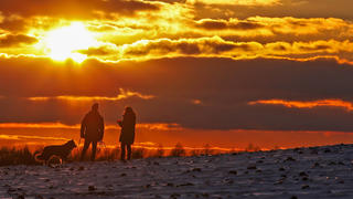  Eiszeit, Frostige Temperaturen, Dauerfrost im Siegerland, ein Eiskalter Tag neigt sich dem Ende, zwei Menschen mit Hund geniessen den Sonnenuntergang in frostiger Landschaft bei Heisberg Winter im Siegerland am 11.02.2021 in Freudenberg/Deutschland. *** Ice age, frosty temperatures, permafrost in the Siegerland, an ice cold day comes to an end, two people with dog enjoy the sunset in frosty landscape at Heisberg winter in the Siegerland on 11 02 2021 in Freudenberg Germany