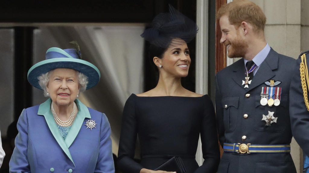 ARCHIV - 10.07.2018, Großbritannien, London: Die britische Königin Elizabeth II., ihr Enkel, Prinz Harry und seine Frau, Herzogin Meghan stehen während einer Flugschau der Royal Air Force auf einem Balkon des Buckingham-Palastes. (zu dpa Bericht: Que